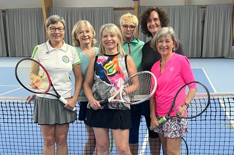 Sechs Frauen in sportlicher Kleidung stehen auf einem Tennisplatz hinter einem Netz, jeweils mit einem Tennisschl&auml;ger in der Hand.